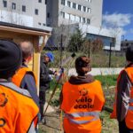 3 membres de la vélo école de dos en train d'observer de loin une lunette astronomique reflétant le soleil sur une feuille de papier