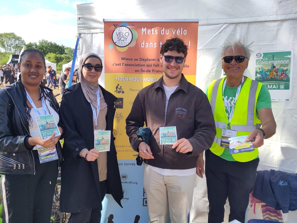 Bénévoles de VéloSQY discutant avec des visiteurs venus pour l'inauguration de la colline devant leur stand présentant des affiches pour le baromètre vélo, la convergence et le VIF.