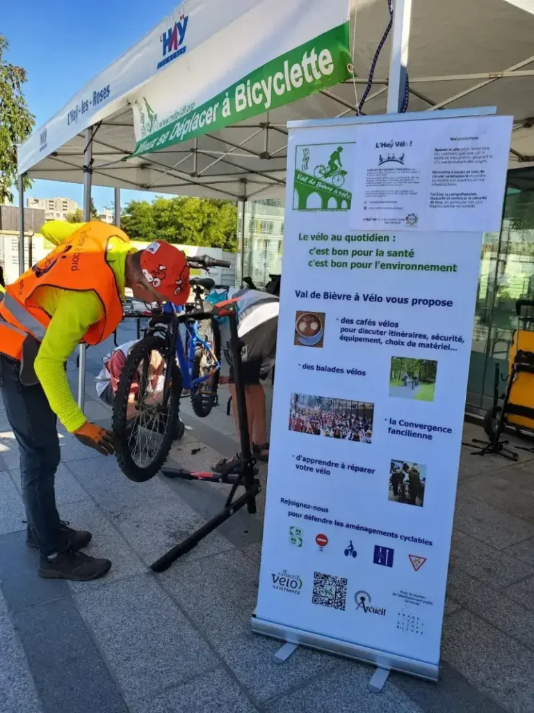 Membres de Mieux se Déplacer à Bicyclette réparants un vélo enfant lors d'un atelier réparation de vélo sur le parvis de la ligne 14 du métro à L'Haÿ-les-Roses